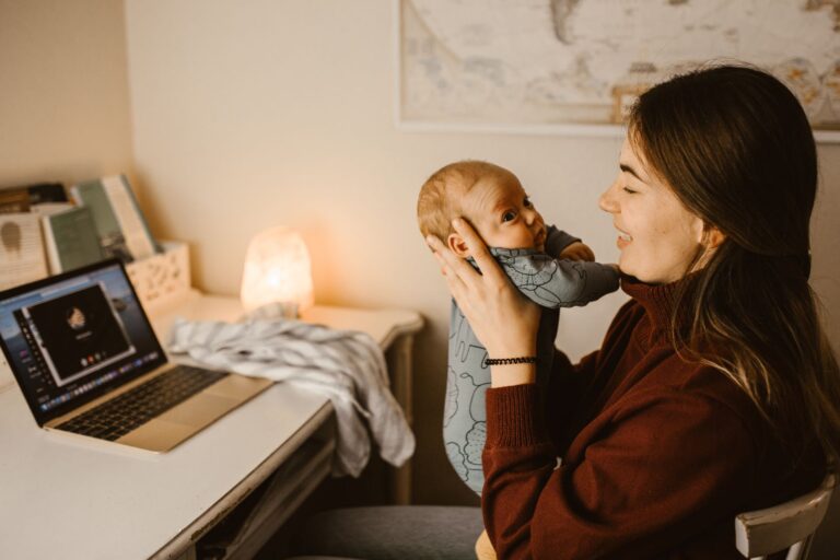 mother holding baby while video calling from home office. cozy and heartwarming indoor scene.