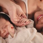 a mother and her newborn holding hands, capturing a tender moment of love.