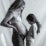 a heartwarming black and white image of a pregnant mother and her child sharing a tender moment indoors.