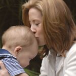 a tender moment between mother and baby, captured outdoors with warm, loving expressions.