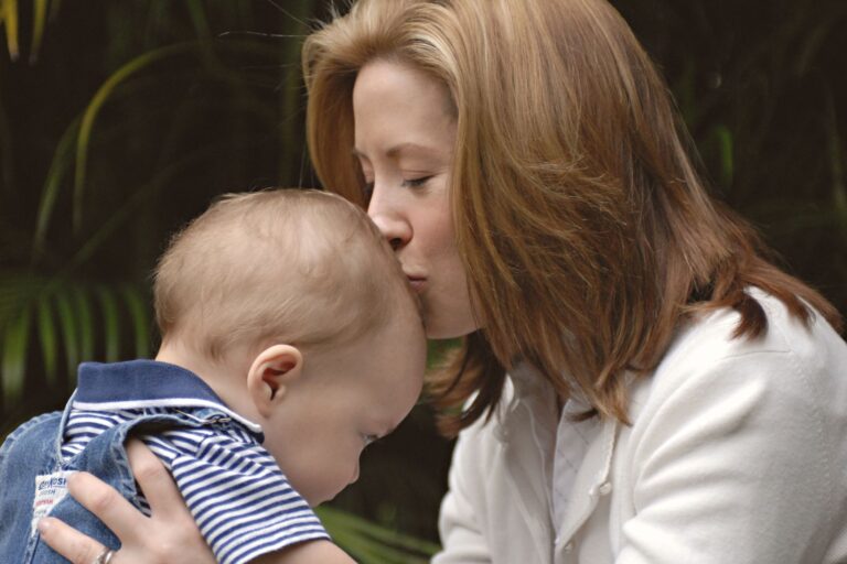 a tender moment between mother and baby, captured outdoors with warm, loving expressions.
