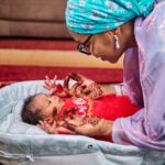 a mother with henna holds her baby in a loving indoor scene in kaduna, nigeria.