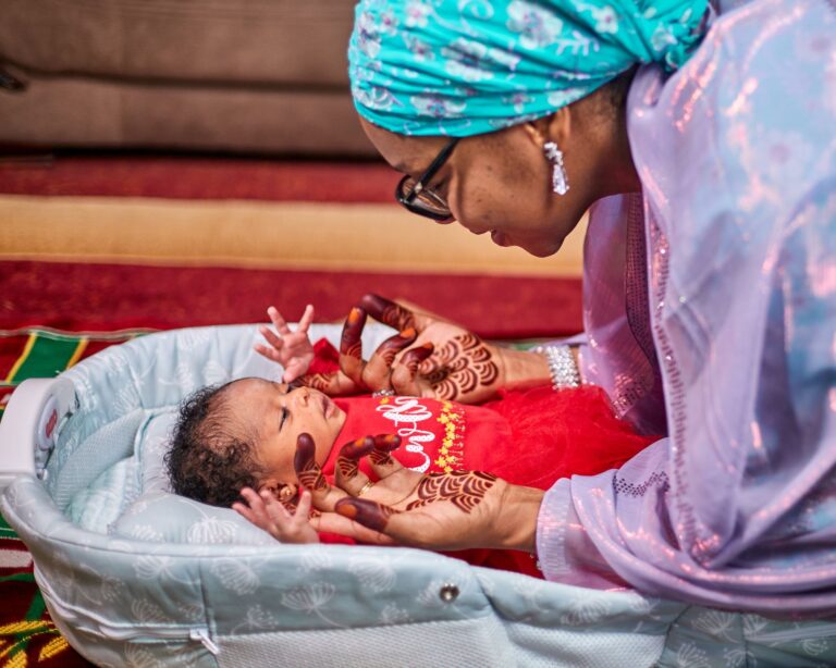 a mother with henna holds her baby in a loving indoor scene in kaduna, nigeria.