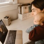 a happy mother and her baby making a video call on a laptop to connect with a loved one from home.