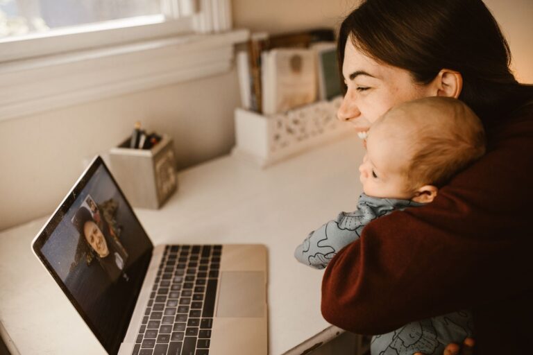 a happy mother and her baby making a video call on a laptop to connect with a loved one from home.
