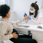 pregnant woman at a nail salon receiving a manicure from a nail technician.