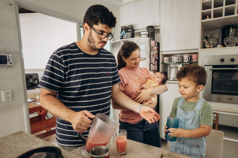 a family bonding moment in the kitchen as parents prepare juice for their children.