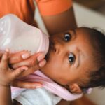 close-up of a mother feeding her baby with a milk bottle indoors.