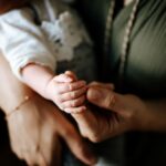 close-up of a mother holding her baby's hand, capturing a tender and intimate moment.