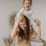 mother and daughter enjoying a playful moment indoors, smiling and happy.