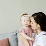 tender moment of a mother kissing her baby daughter. warm and loving family scene indoors.