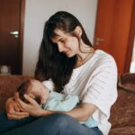 a tender moment captured between a mother and her baby in a cozy bedroom setting.