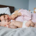 a mother and her baby lying on a bed, showcasing a bond of love and warmth indoors.
