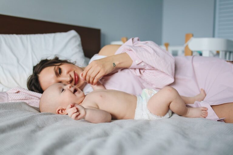 a mother and her baby lying on a bed, showcasing a bond of love and warmth indoors.