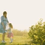 pregnant mother with daughter enjoying a sunny day outdoors.