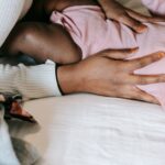 high angle of crop anonymous african american mother stroking small infant daughter