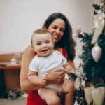 mother and child enjoying festive moments by a decorated christmas tree.