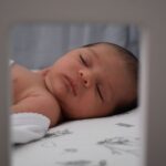 a serene image of a sleeping baby lying peacefully indoors. captured in soft and gentle lighting.
