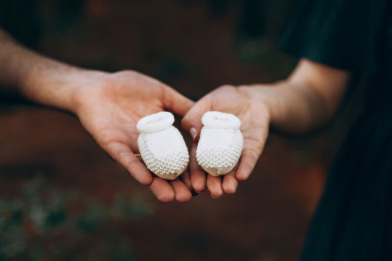 high angle of hands of faceless man and woman demonstrating soft baby booties