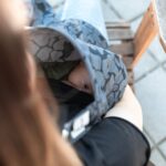 intimate outdoor moment of mother breastfeeding baby under cover on a bench.