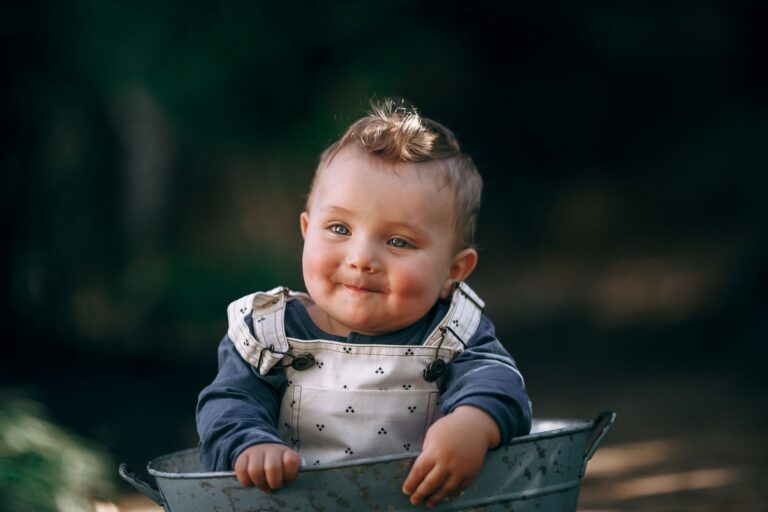 adorable baby with happy expression in nature, wearing overalls.