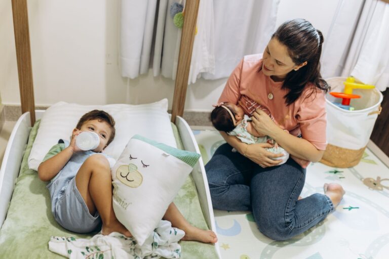 mother with baby and young child in a warm, nurturing nursery environment.