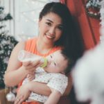 an asian mother happily feeds her baby with a bottle during the christmas holiday season.
