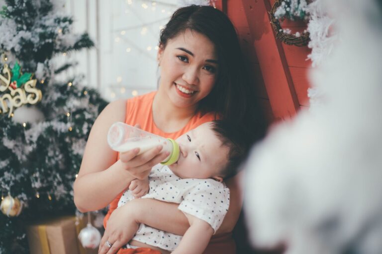 an asian mother happily feeds her baby with a bottle during the christmas holiday season.