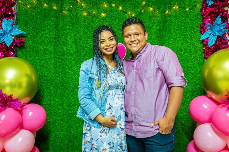 joyful couple at a maternity celebration with colorful balloons and decorations.