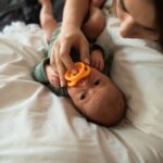 a tender moment of a mother with her newborn baby holding a pacifier indoors.