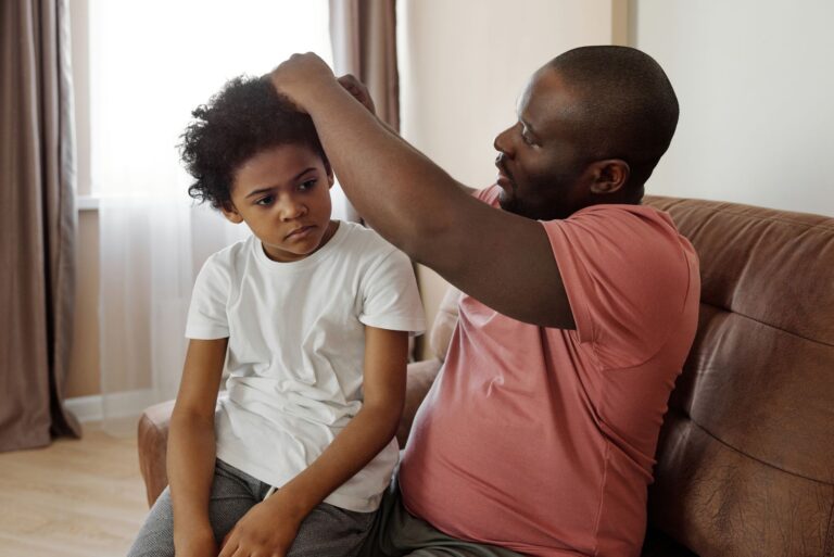 a father lovingly styles his son's hair in a cozy living room setting, showcasing family togetherness.