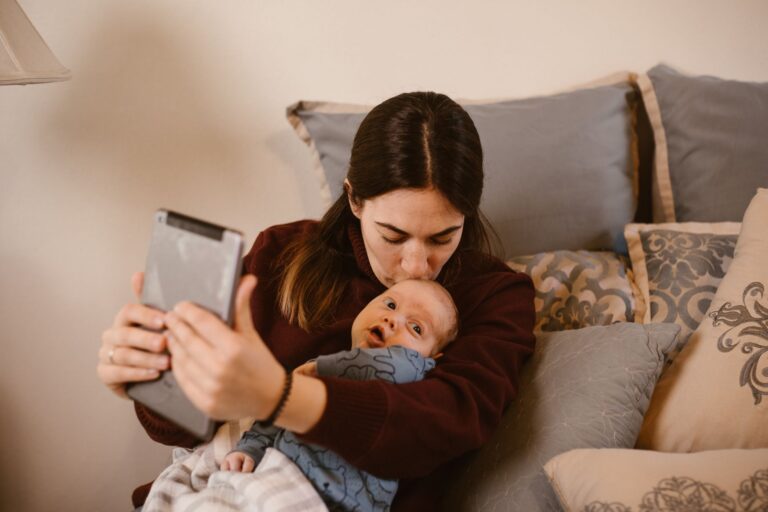 a warm moment captured as a mother kisses her baby while video calling on a tablet.