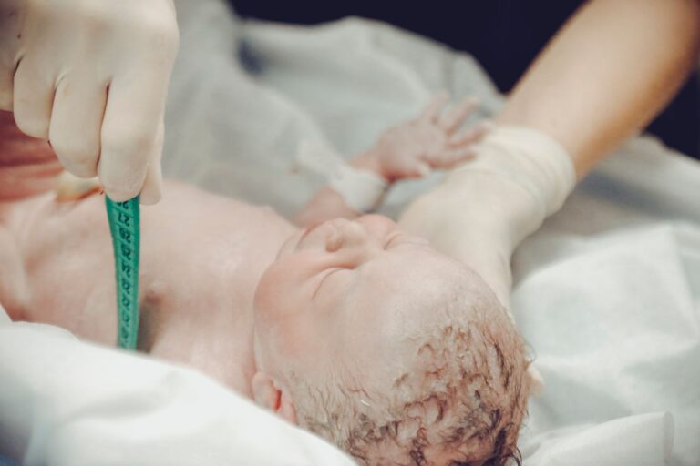 a newborn baby being measured by a medical professional in a hospital setting.