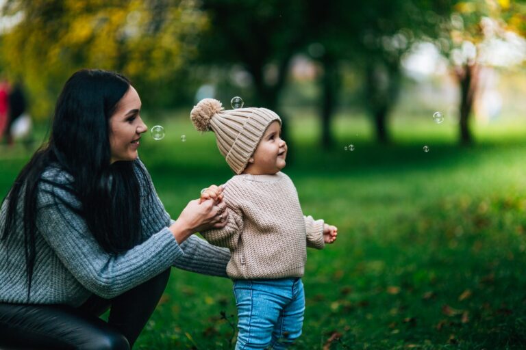 a joyful moment with mother and child playing with bubbles outdoors in a park.