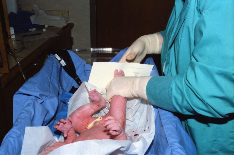 a nurse tends to a newborn baby in a hospital delivery room setting.