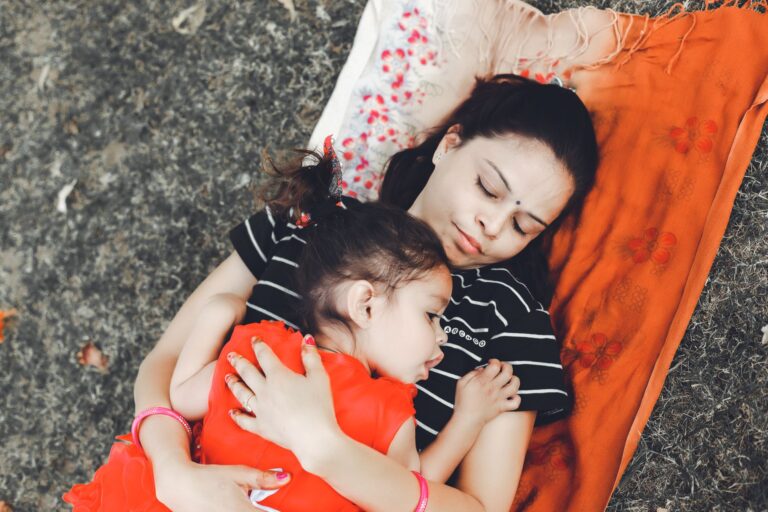 mother and daughter lying on blanket outdoors, showcasing love and connection.