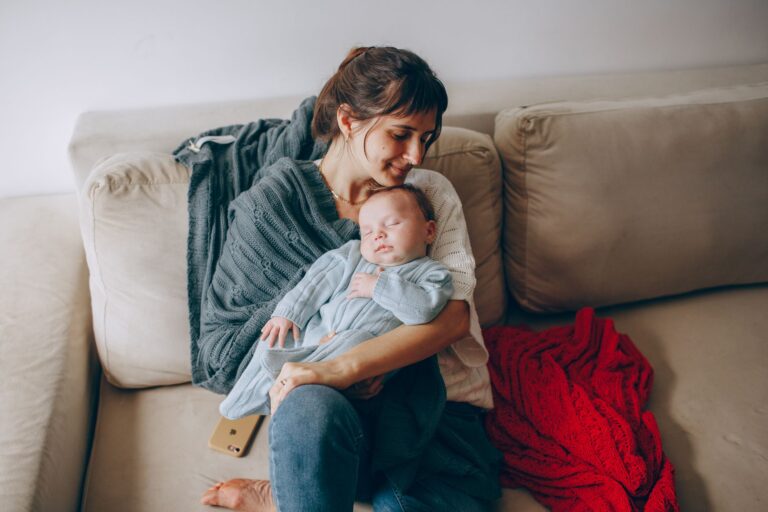 a tender moment of a mother cradling her sleeping baby on a cozy sofa.