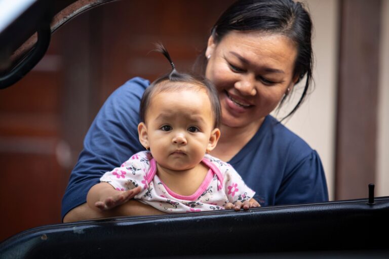 a mother joyfully holds her baby, showcasing a moment of family affection and happiness.