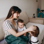 a mother lovingly cares for her two young children in a cozy home environment, creating a warm family moment.