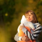 a serene moment of a mother cuddling her baby outdoors during the day.