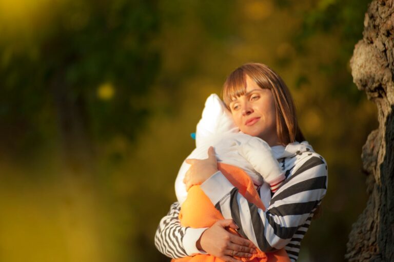 a serene moment of a mother cuddling her baby outdoors during the day.