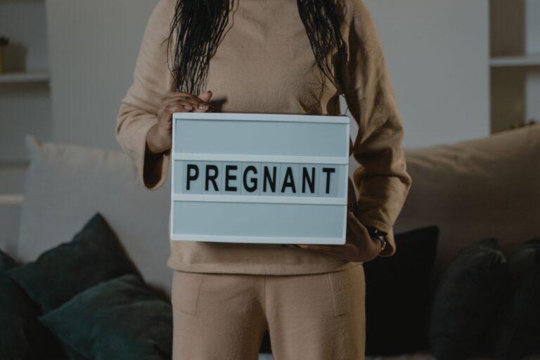 a woman in beige holds a lightbox with 'pregnant' indoors. expectant motherhood concept.
