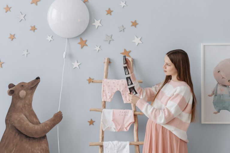 expectant mother holding ultrasound images in a beautifully decorated nursery with whimsical elements.
