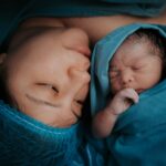 a touching image of a mother and her newborn baby wrapped in blue medical blankets.