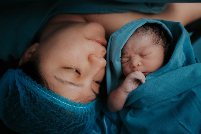 a touching image of a mother and her newborn baby wrapped in blue medical blankets.