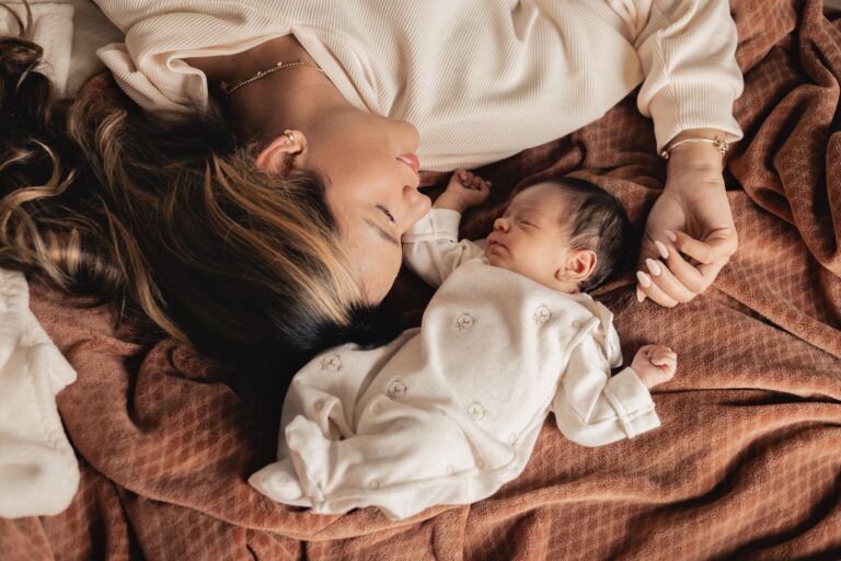 a tender moment of a mother and her newborn baby sleeping together on a soft blanket.