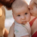 a tender moment of parents kissing their baby, highlighting love and family bonds.