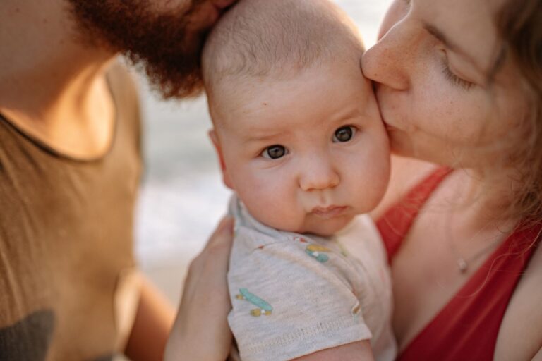 a tender moment of parents kissing their baby, highlighting love and family bonds.