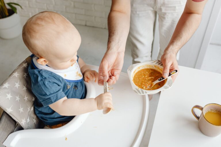 a cute baby in a high chair being fed by a parent, creating a warm family moment.