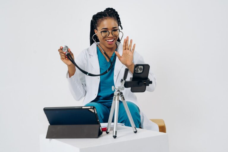 smiling female doctor using stethoscope during a telehealth video call.